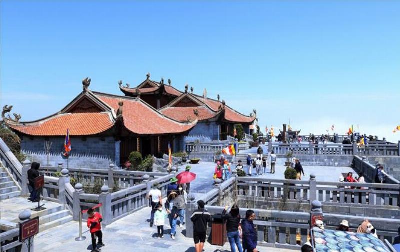 Một du khách đang đứng trên Sân Mây Núi Hàm Rồng, tay giang rộng, mây trắng bồng bềnh bao quanh